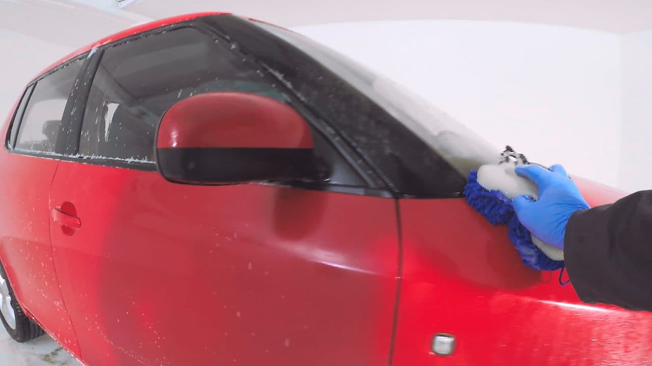 Ręka myjąca czerwony samochód z zewnątrz