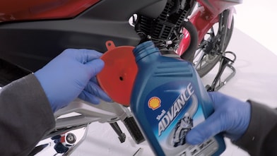 ręce trzymające nowy olej motocyklowy Shell Advance