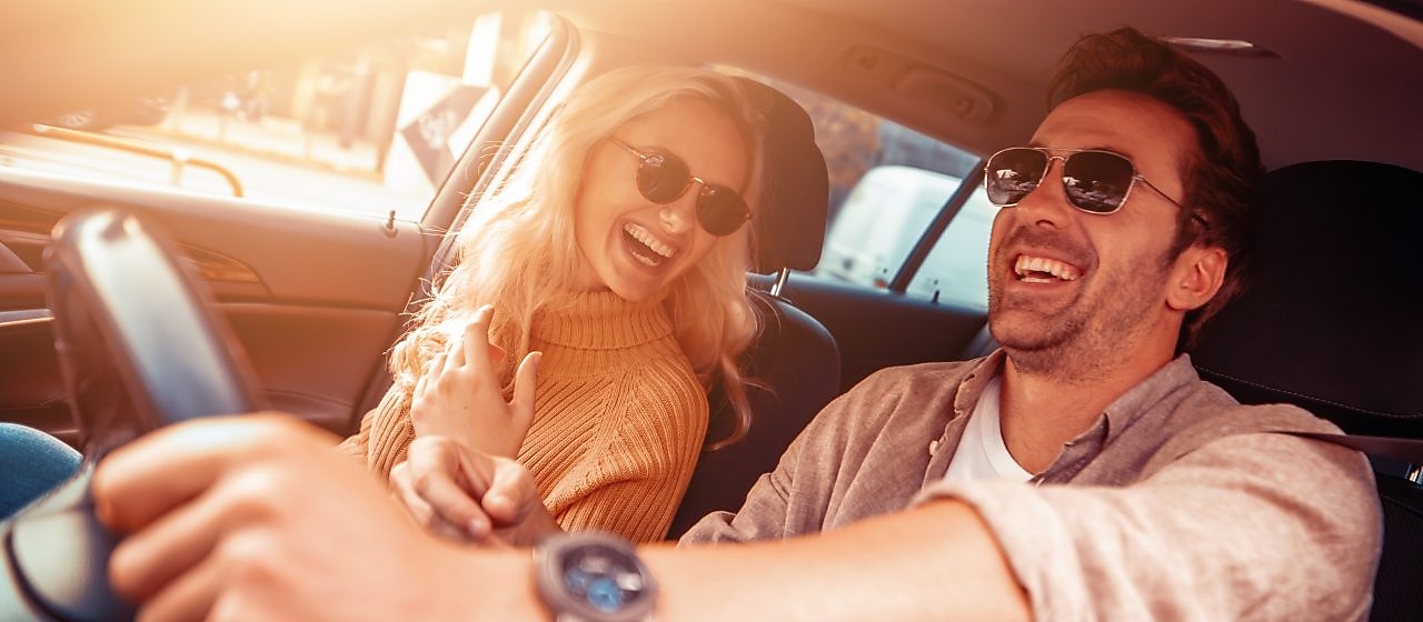Zdjęcie przedstawiające zadowoloną parę jadącą samochodem