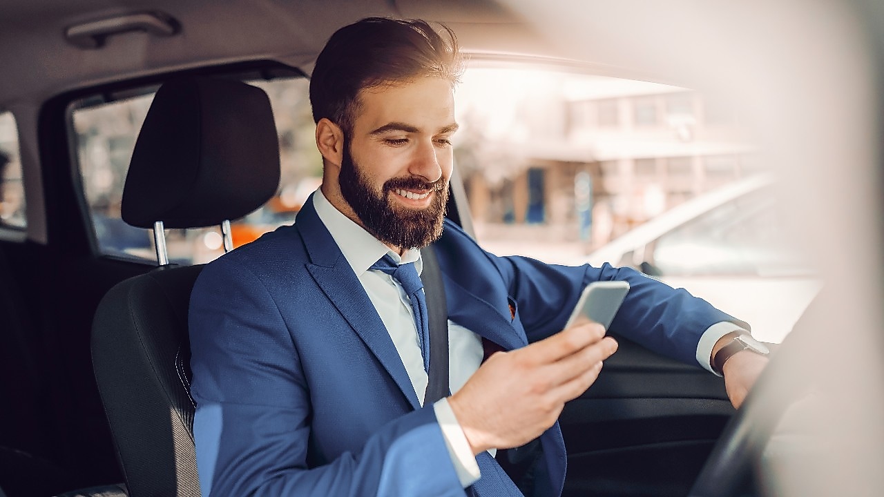 Zdjęcie z zadowolonym mężczyzną sprawdzającym aplikację Shell ClubSmart w telefonie