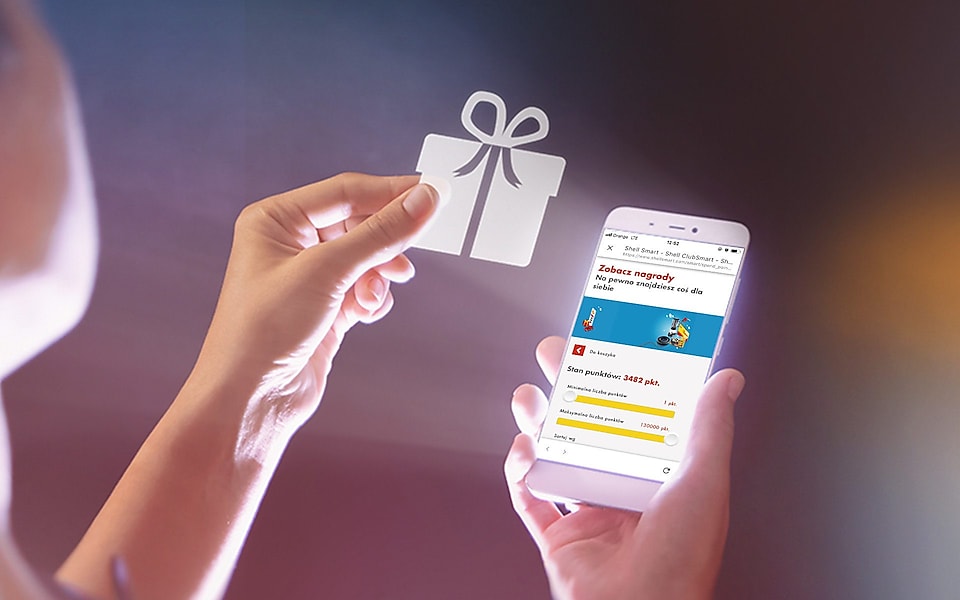 Telefon z aplikacją Shell ClubSmart i dłoń trzymająca ikonę prezentu, co oznacza korzyści dla użytkowników. 