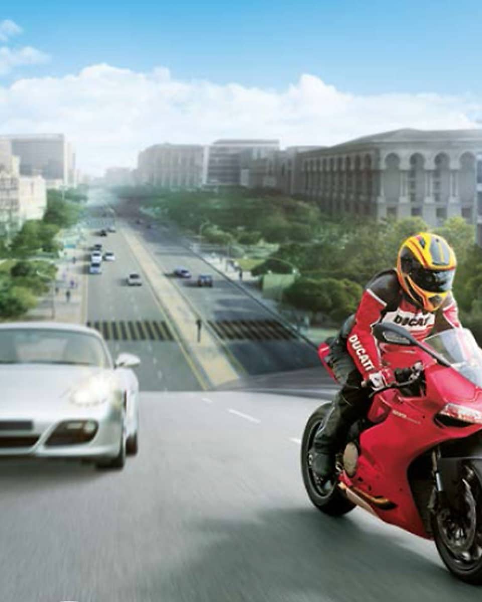 Czerwony motocykl i motocyklista na drodze między samochodami z budynkami w tle