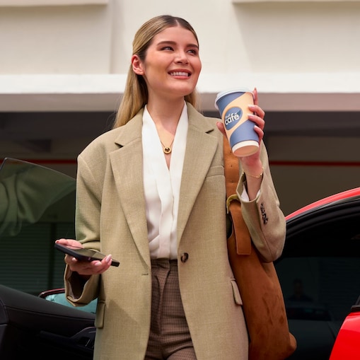 Zdjęcie przedstawia zadowoloną kobietę pijącą kawę Shell Café